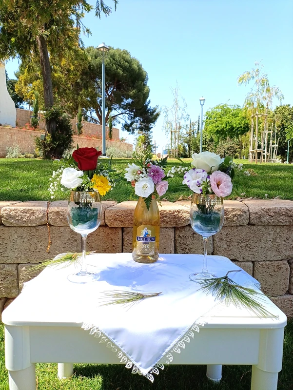 סידור פרחים לבקבוק יין ושתי כוסות